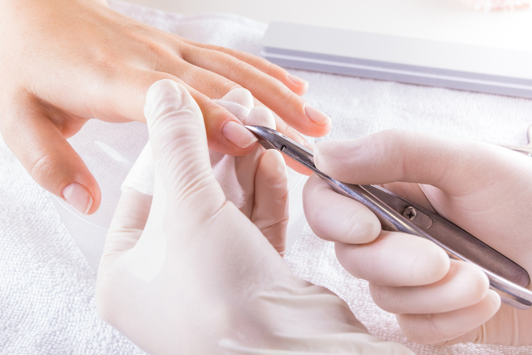 The master in the salon makes the client a manicure.